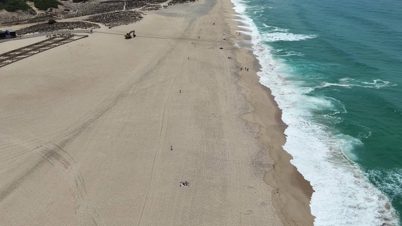 Aerial view of a sandy beach with waves and people