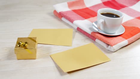 cup of black coffee, envelope and gift box on wooden surface 4k