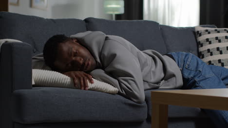 unhappy and depressed young man lying on sofa at home looking anxious and worried