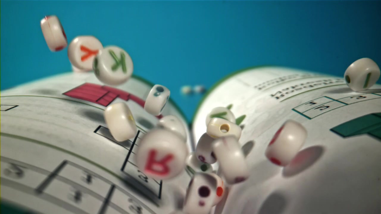 Alphabet Letter Beads Falling onto Pages of an Open Book