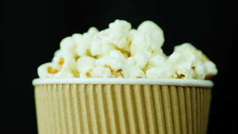 A-Glass-Of-Mouth-Watering-Popcorn-Smoothly-Rotates-Against-A-Black-Background-Food-For-Watching-Movi