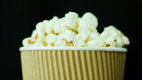 un bicchiere di popcorn da leccarsi i baffi ruota dolcemente su uno sfondo nero cibo per guardare i film