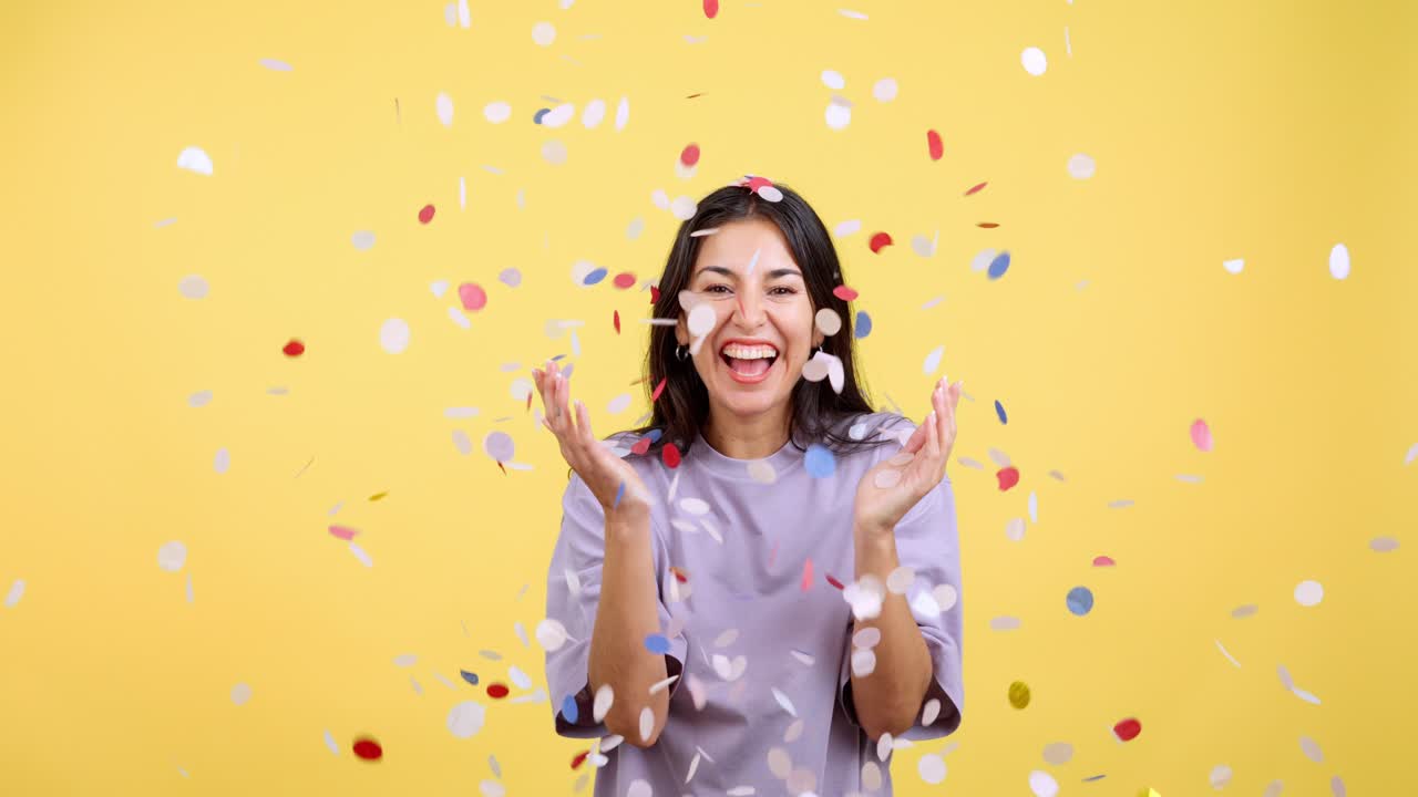 Happy Woman Celebrating with Confetti on Yellow Background