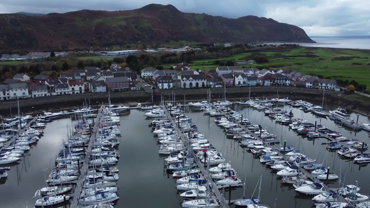 산악 해안선 조감도 오른쪽 하강 아래 경치 좋은 고급스러운 해안가 항구 아파트 마을 요트와 범선