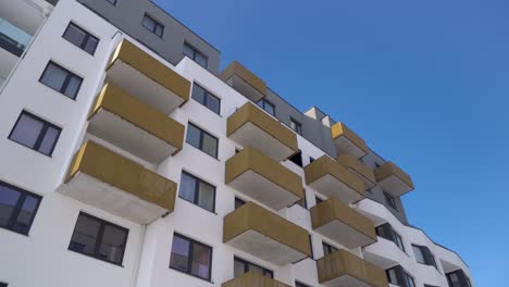 modern-block-of-flats-with-balconies-on-a-sunny-day-with-blue-sky,-truck-right