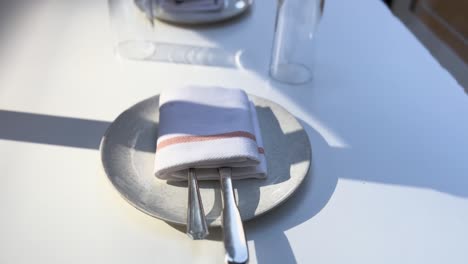 fine dining white table setting with cutlery napkin plate and glass