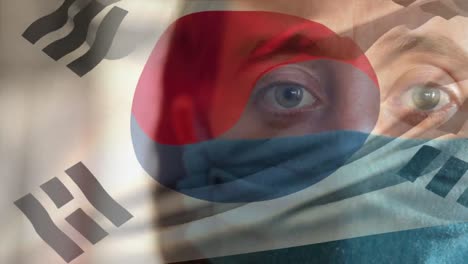 animation of flag of south korea over caucasian man in face mask