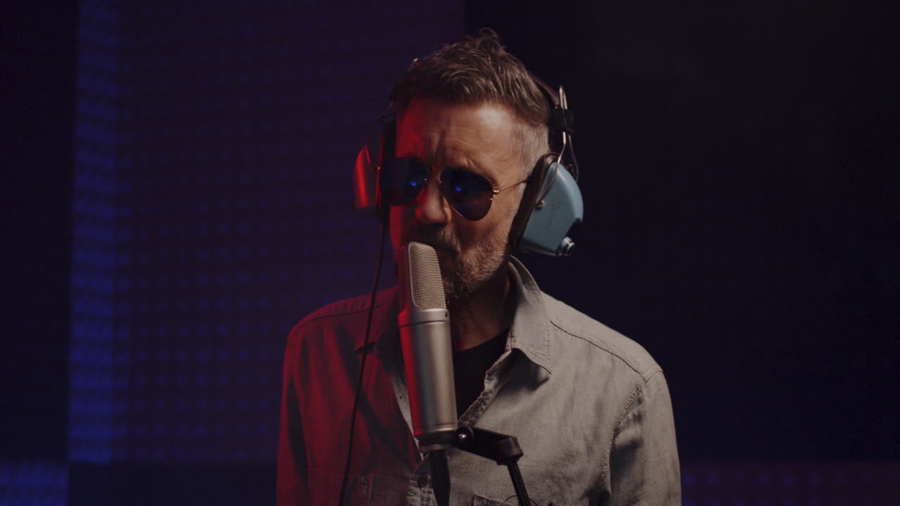 Talented Singer Records Hit with Microphone in Audio Studio Talented Blonde Woman Singer with Black Earphones Records New Hit with Microphone in Semidark Modern Soundproof Audio Studio Extreme Close View