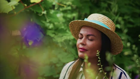 woman wearing straw hat enjoying nature in a lush garden surrounded by vibrant greenery