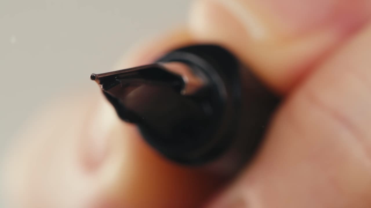 Close-up of Fountain Pen Writing 'Hello World' on Transparent Surface