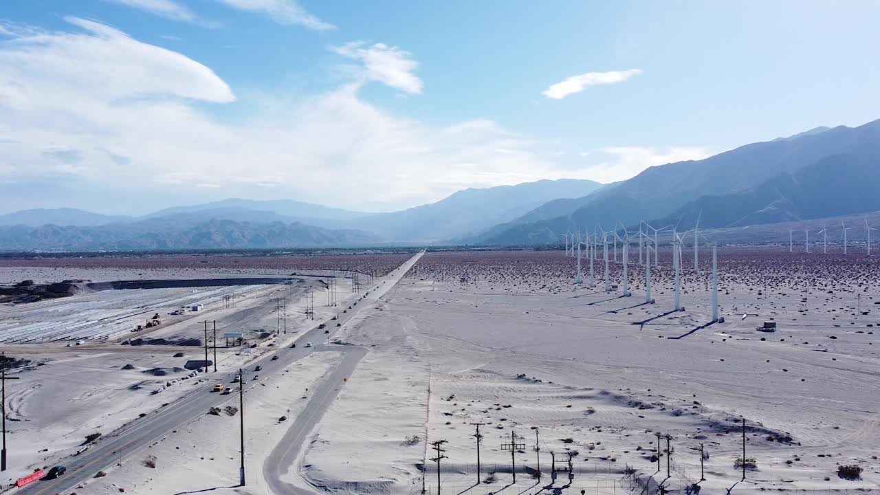 거대한 풍력 터빈 농장 근처의 사막 고속도로에서 운전하는 자동차, 공중 측면 플라이 뷰