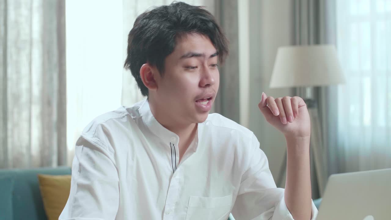 Close Up Of Asian Man Student Raises Hand And Asks Teacher A Question While Using Computer To Study Online At Home