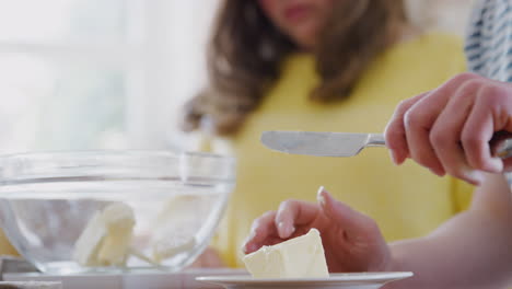 cerca de la pareja del síndrome de down añadiendo mantequilla a la receta del pastel que están horneando en la cocina en casa