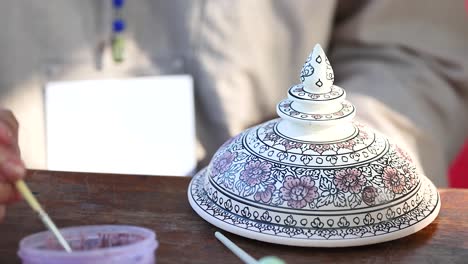 close-up of artist carefully painting traditional thai ceramic bowl