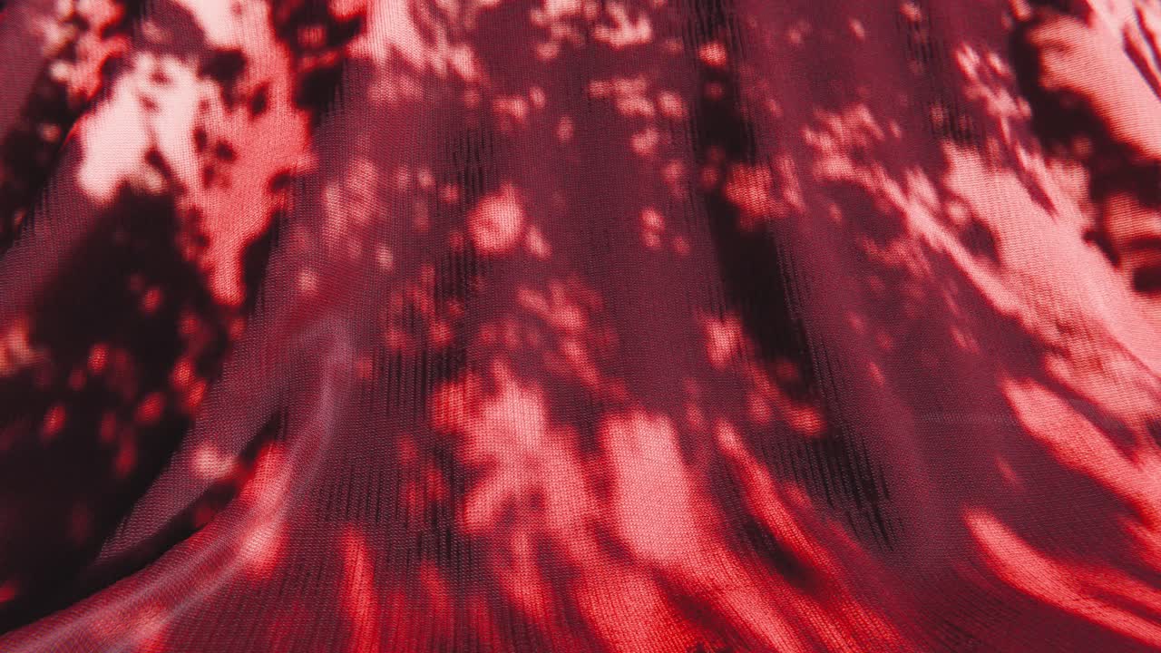葉の影のパターンが映る抽象的な赤い布のテクスチャ