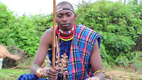 young maasai man tapping his staff to beat of music