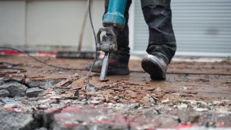 un trabajador de la construcción que usa un martillo neumático para quitar el hormigón viejo cerca de la casa - primer plano