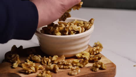 un primer plano de una persona recogiendo un puñado de nueces de un cuenco en el estudio