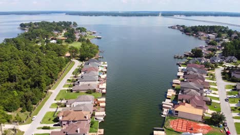 Una-Toma-Aérea-De-Casas-Junto-Al-Lago,-Cerca-De-Un-Campo-De-Golf,-En-Un-Día-Soleado,-Grabada-En-60-Fotogramas