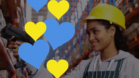 Animation-of-blue-and-yellow-hearts-over-biracial-female-worker-in-warehouse