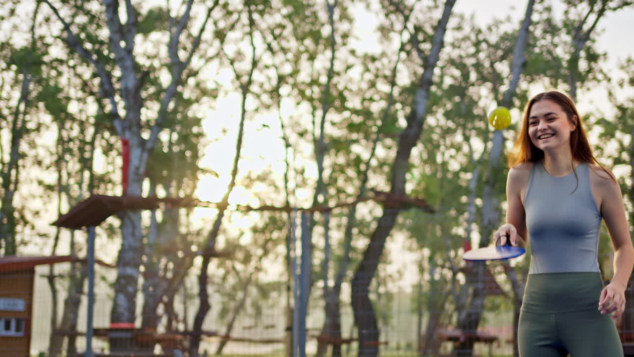 Woman playing pickleball on a blue and green court after rain