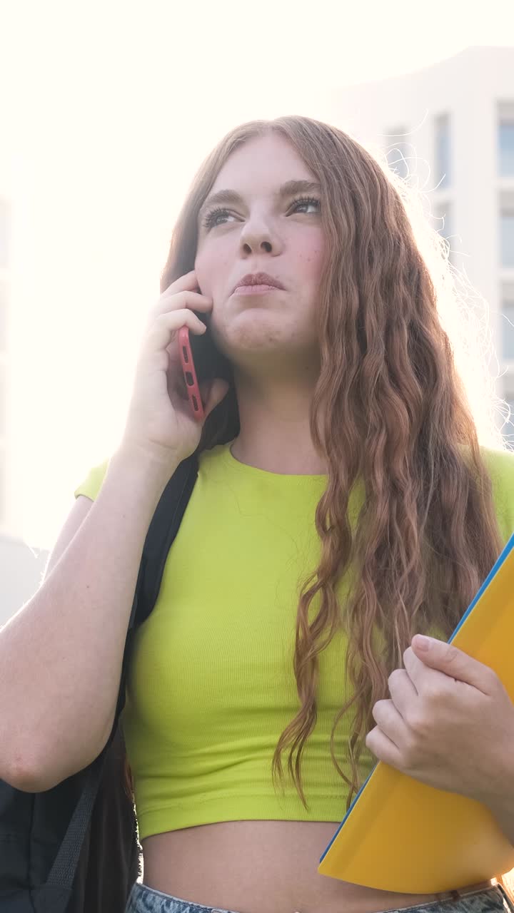 Student talking on phone walking near college