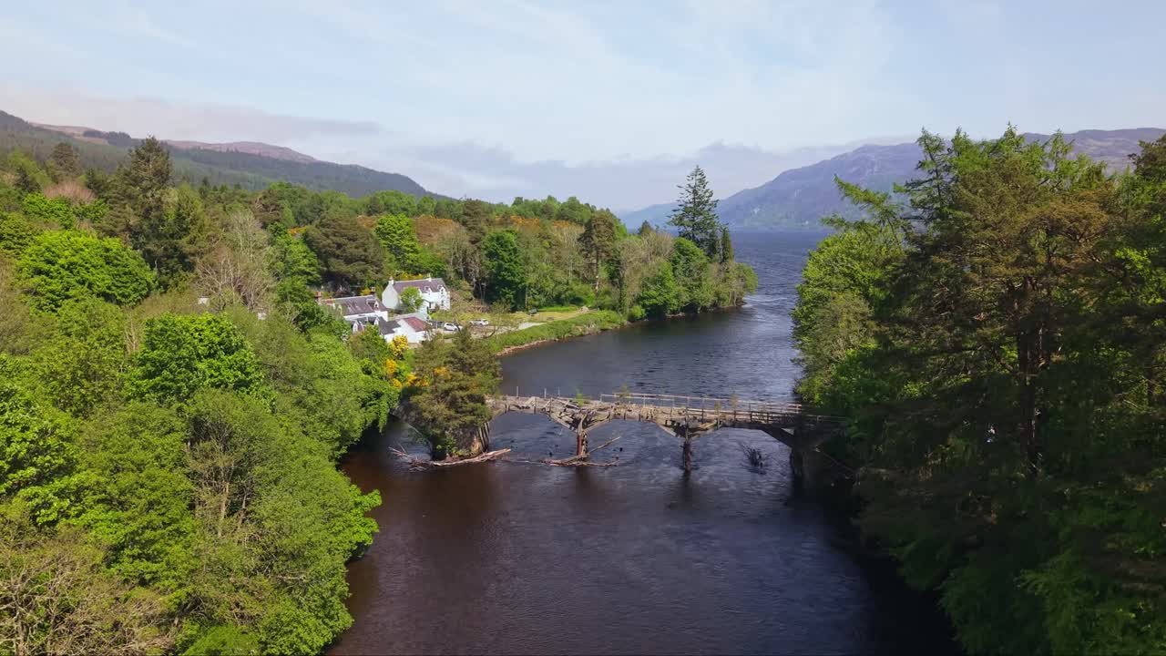 Drone footage revealing the scenic Loch Ness landscape as seen from the charming old wooden bridge at Fort Augustus, with lush Highlands in the background