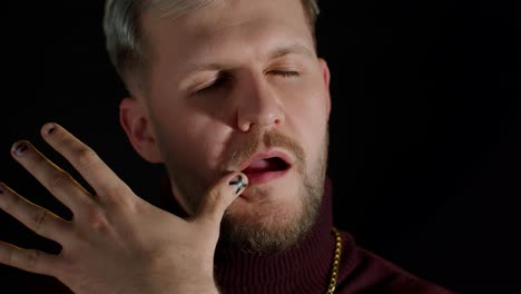 confident bearded man in stylish clothing sensually touching lips with finger on black background