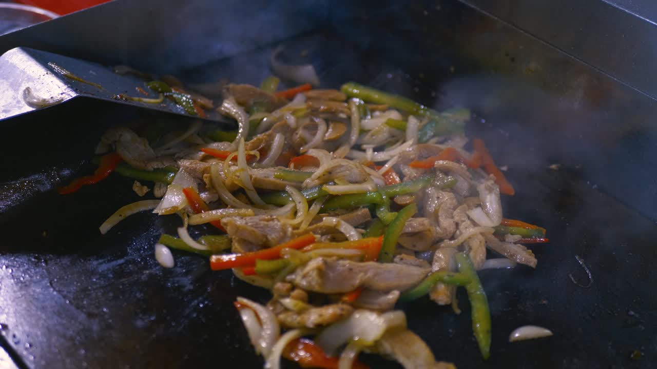 Sauteed vegetables in a pan with sliced chicken, onion and red and green bell peppers