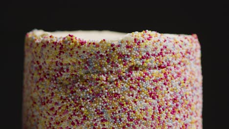 close up studio shot of revolving birthday cake covered with hundreds and thousands decorations 6