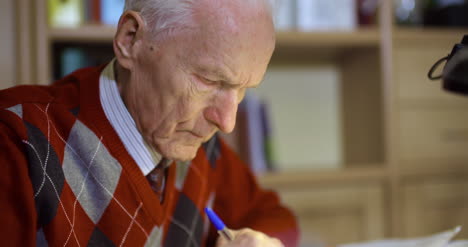 Senior-Businessman-Writing-On-Paper-At-Table-In-Office-34