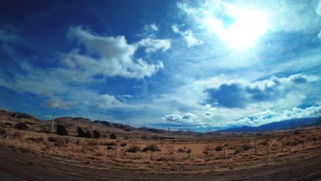 conduciendo por una carretera del sur de california con turbinas eólicas en las colinas generando energía limpia - punto de vista