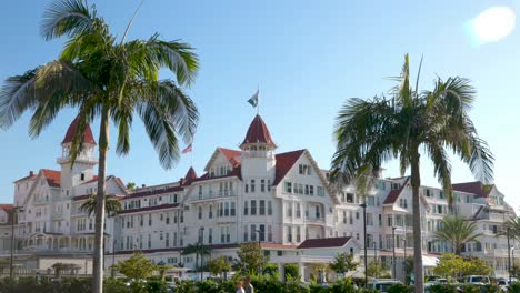 4K-Video:-Hotel-Del-on-Coronado-Island,-Warm-Sunny-Summer-Day,-Blue-Skies,-Palm-Trees-Blowing,-People-and-Cars-Passing-By---2023