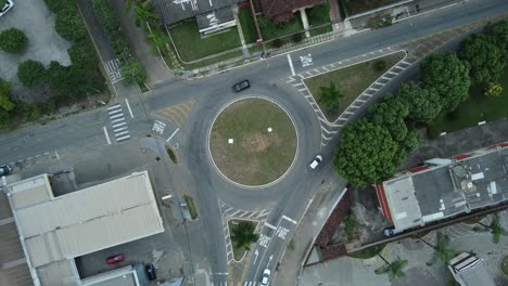 Top-down-aerial-drone-view-of-a-small-traffic-roundabout-on-a-quiet-road