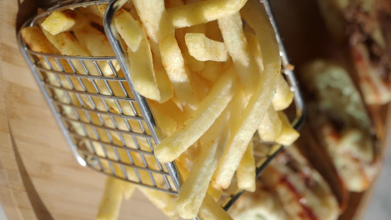 Patatas fritas doradas en una cesta de metal sobre una tabla de madera