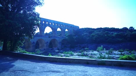 shot of the pont du gard in france in the evening behind some trees in nature over a river