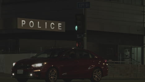 establishing the local police station building entrance signage at night with some traffic movement in the foreground, tilt down reveal shot