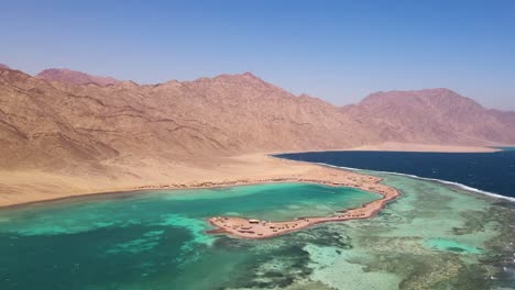 Aerial-view-of-the-blue-lagoon-in-Dahab,-Egypt,-offers-stunning-views-of-the-nearby-desert-landscape,-promising-visitors-an-unforgettable-and-incomparable-adventure