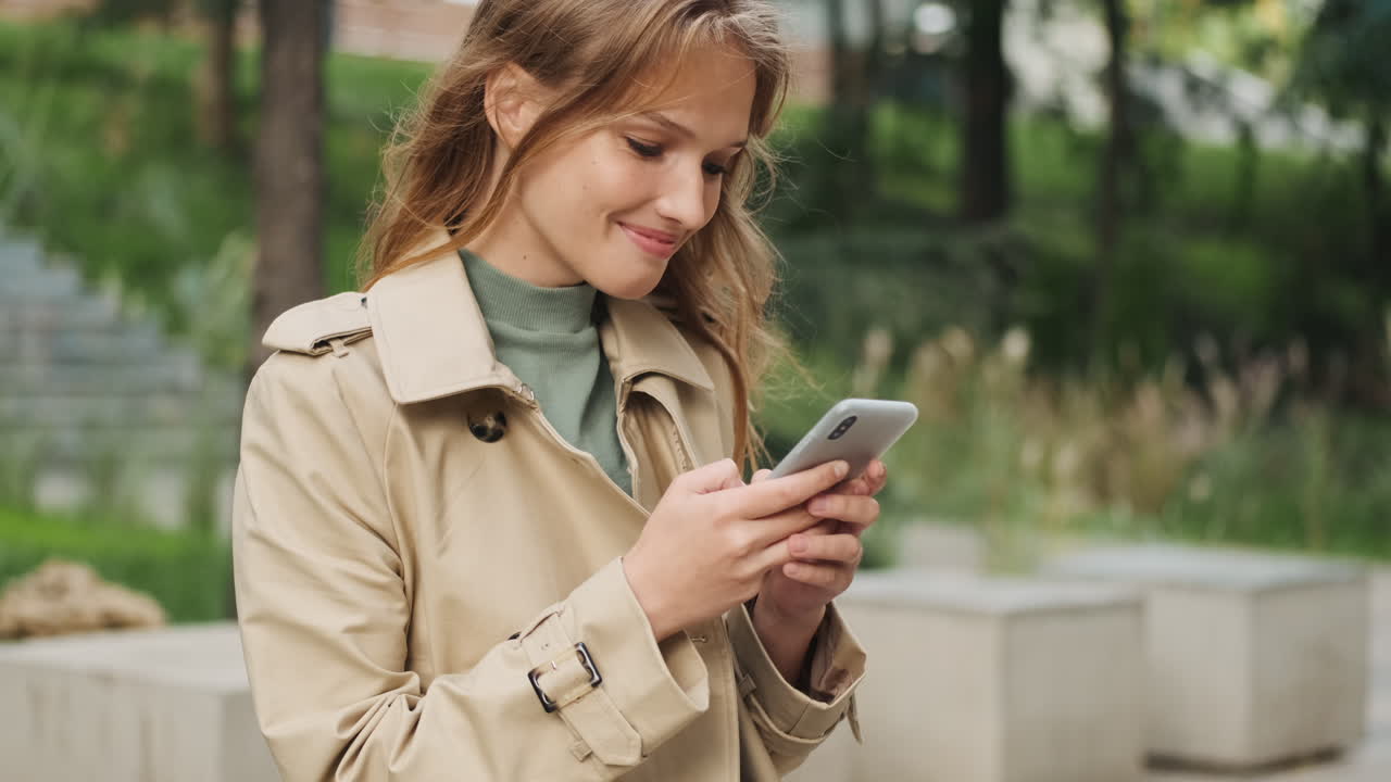 Caucasian female student using smartphone outdoors.