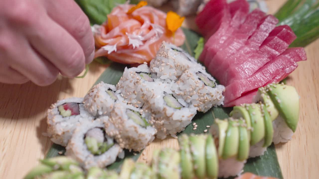 A rising shot captures a chef adding decorative touches to sushi rolls, showcasing culinary artistry and attention to detail. Ideal for sushi, culinary, and food presentation content.