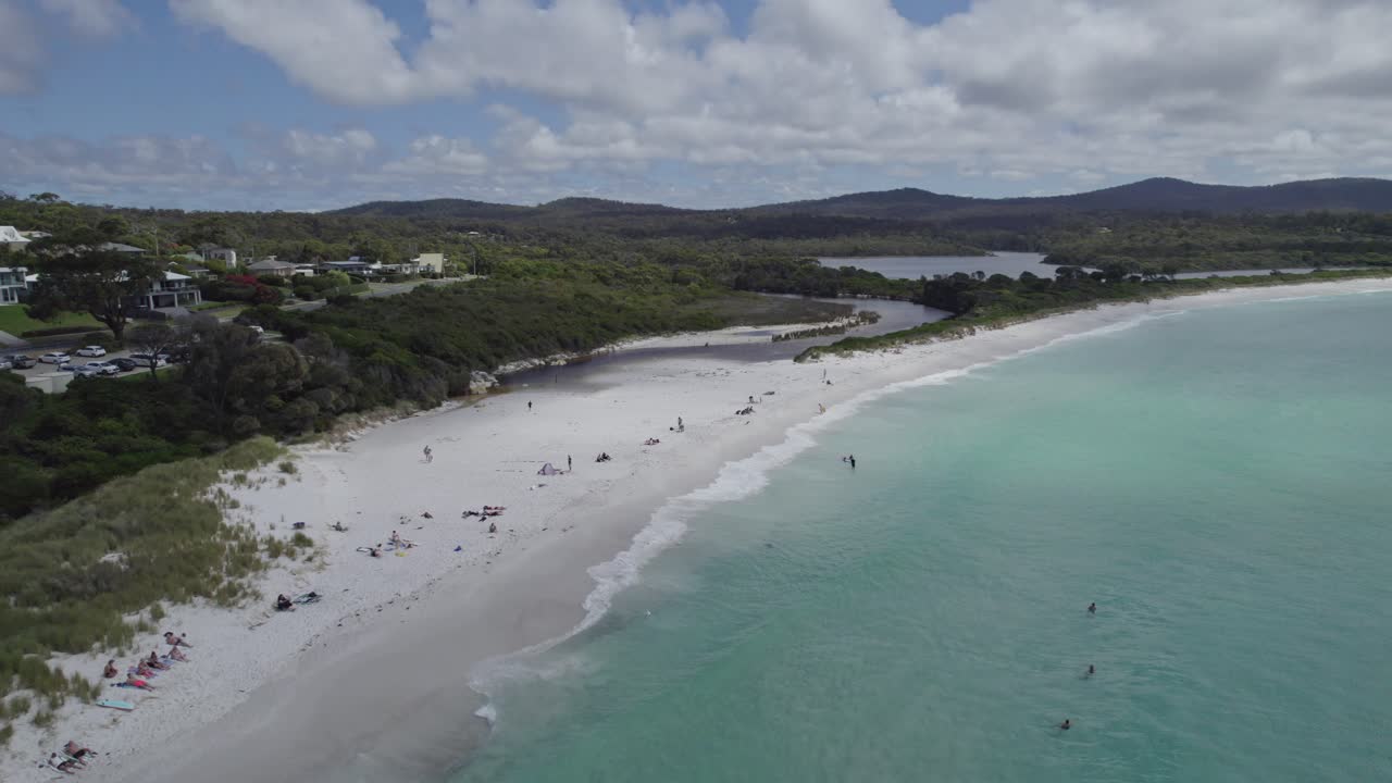 los bañistas nadando en las aguas cristalinas de la playa de la bahía de binalong en tasmania, australia