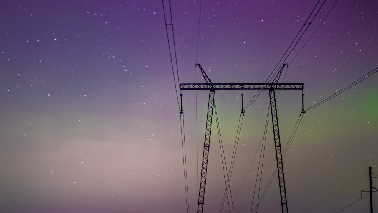 Aurora Borealis and night starry sky above high voltage power lines, time lapse
