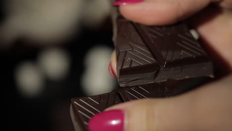 woman breaks black chocolate bar. close-up. slow motion