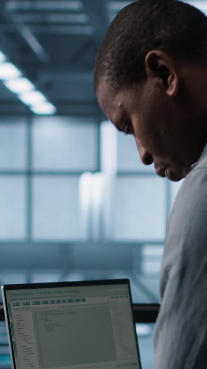Vertikales Video: Ingenieur im Rechenzentrum bedient Notebook, implementiert neue Serverarchitekturen.