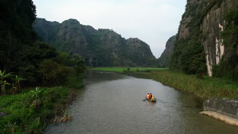 turistas viajam em barco sampana no rio ngo dong em ninh binh vietnã - tiro aéreo revelador