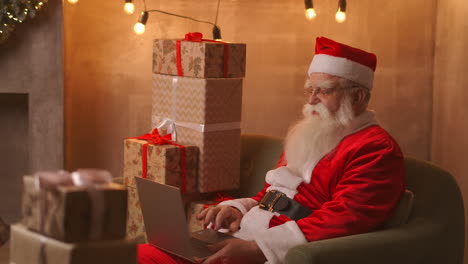 santa claus video llamando tak al niño en el portátil mantener presente sentarse en la mesa de casa. pandemia y el aislamiento de la santa felicita a los niños remotamente. imágenes de alta calidad 4k
