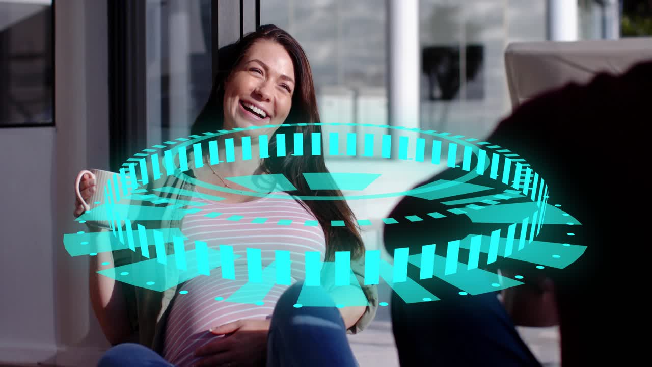 Pregnant woman sipping mug, touching belly, laughing while friend talking, cyan ring showing health