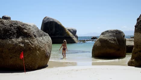 chica caminando sobre el agua en la playa 4k