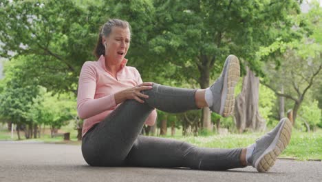 Senior-woman-in-pain-holding-her-leg-in-the-park