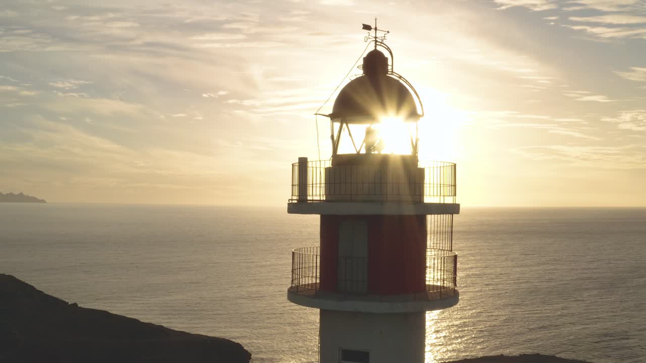 toma cercana de un faro con sol y océano en el fondo a la hora dorada